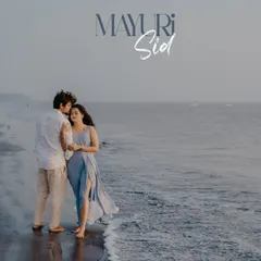 A romantic pose at the water's edge, with the groom kissing the bride's forehead as waves gently lap the shore.
