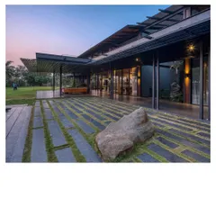 The Lakeshore house at dusk, a filter for breezes and views on Lake Osman Sagar. Here, a prefabricated steel skeleton and walls of rammed earth from the site itself come together, creating a home that almost disappears into the treeline.