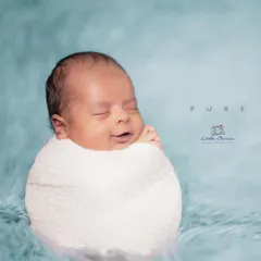 This is a classic 'potato sack' swaddle pose, which babies often find very comforting. The simple wrap and soft blue backdrop draw all the attention to the baby's sweet, sleepy smile.