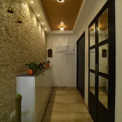 A stunning foyer design that balances textures beautifully. The rough stone-cladding on one wall is contrasted with sleek, mirrored doors and a warm wooden ceiling, creating a sophisticated entrance.