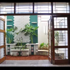 Viewed from the interior, the compact courtyard at the Prabhakar Residence acts as a living mural. Large wooden doors fold away to completely open up the living space to this private, plant-filled sanctuary.