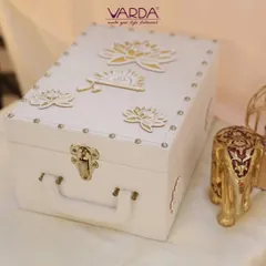 This elegant white trunk-style box is adorned with golden lotus motifs. It's a versatile and luxurious keepsake box that can be used for wedding invitations, trousseau packing, or as a decorative storage piece.