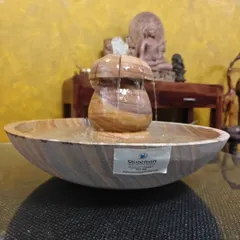 This lightweight tabletop fountain is made from Rainbow Sandstone, showcasing the stone's natural wood-like patterns. It's pictured here on a glass table in a living room setting.