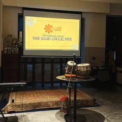The stage is set for an evening of music and community. With a simple setup of a keyboard, tabla, and a microphone, we transform the room into an intimate musical gathering.