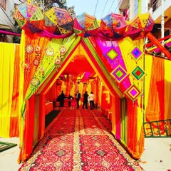 No space is too challenging. Here, I've converted an outdoor area into a grand, festive venue with a colourful tent entrance, perfect for a Haldi or Mehendi ceremony. The setup includes traditional Rajasthani umbrellas and intricate drapery.