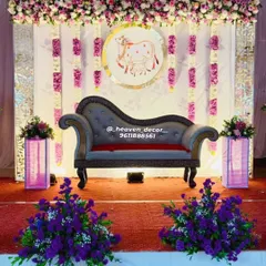 A beautiful stage for a Seemantha or baby shower ceremony. The decor features a custom backdrop with a traditional cow motif, symbolizing motherhood, framed by elegant floral arrangements in purple and white.