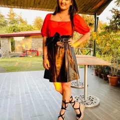 A full-length shot of the look I styled for Haryanvi artist Anjali Raghav. The combination of the bright red puff-sleeve top and the black faux leather skirt with lace-up wedges creates a stylish, contemporary outfit.