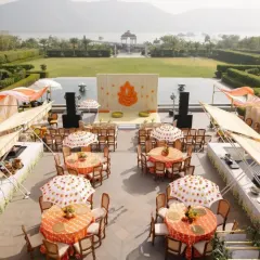 An aerial view of a traditional Haldi ceremony setup at Raffles, Udaipur. The classic yellow and orange theme is executed with elegance, featuring patterned tablecloths and custom umbrellas.