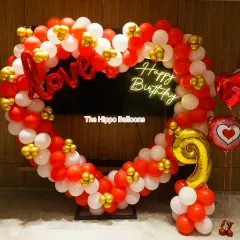 A heart-shaped balloon frame in red, white, and gold. This decoration includes "Love" and "Happy Birthday" signs, making it a perfect photo booth for a 9th birthday or an anniversary.