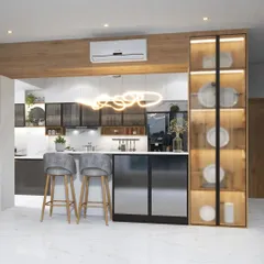 This stunning parallel kitchen features a breakfast bar, sleek gray cabinets, and a lit-up glass crockery unit. The design is perfect for open-plan living, blending the kitchen seamlessly with the dining area.
