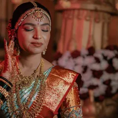 A serene moment captured of a beautiful South Indian bride. Her makeup features a warm, golden shimmer on the eyes and a perfectly blended base to complement her silk saree and heavy temple jewelry.