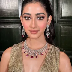 A direct, confident gaze. The makeup is perfectly balanced to complement the ruby and diamond jewelry, creating a cohesive and glamorous party look.