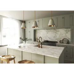 A beautiful kitchen with sage green cabinetry and a stunning marble countertop and backsplash. The brass fixtures and concrete pendant lights add a touch of modern industrial charm to the classic shaker-style cabinets.