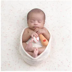 A home run of a photo. This newborn is posed with a miniature baseball and bat, a perfect theme for a sports-loving family.