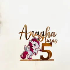 Bring a touch of magic to your child's birthday with a unicorn-themed topper. This piece for "Anagha turns 5" combines rose gold acrylic lettering with a colorful printed unicorn for a fun, storybook feel.