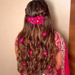 Fresh floral happiness! This half-updo with bright pink flowers scattered through the curls is a classic and beautiful choice for a Haldi or Mehendi ceremony.