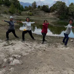 A group of us holding Virabhadrasana II (Warrior II) pose by a serene mountain lake. Practicing with others in nature amplifies the feeling of connection to the earth and each other.