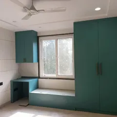 A delivered project featuring a custom-designed bedroom unit in a beautiful teal color. The design includes a wardrobe, a study desk, and a window seat.
