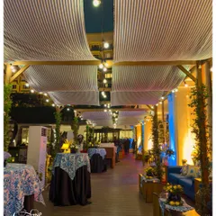 A full view of the pergola-covered walkway. I used striped fabric draping and string lights overhead, with intimate seating areas and food stations along the side, to evoke the feeling of a seaside Italian market.