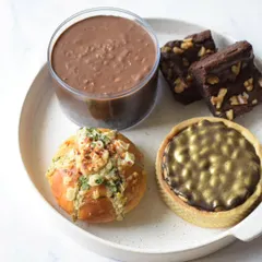 My Rakhi Delight Box is a perfect mix of sweet and savory. It includes Walnut Brownies, a Snickers Caramel Tart, a Chocolate Dream Cake, and one of my savory Korean Cream Cheese Buns.