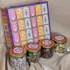 This hamper showcases a beautiful box with a traditional 'jharokha' design, paired with four glass jars filled with assorted dry fruits and nuts. The lids are coordinated with the box design for a complete, elegant look.
