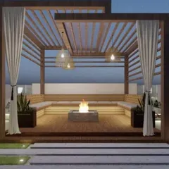 We designed this elegant rooftop lounge with a wooden pergola, built-in bench seating, and a central fire pit. The addition of flowing curtains and pendant lights creates a private, resort-like feel perfect for cool evenings.