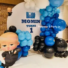 A fun "Boss Baby" themed first birthday party for Momin. The decoration includes a custom backdrop, character cutouts, and a balloon arrangement in the theme's signature blue, black, and white colors.