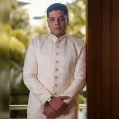 A strong and composed portrait of the groom. The indoor lighting and his direct pose create a formal and sophisticated look, highlighting his wedding attire.