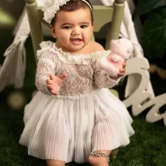 This image captures the interactive and playful side of a sitter session. The baby reaches out with a happy expression, showing off her personality while holding a small toy.