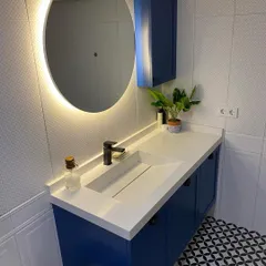 We love adding a pop of color to make a bathroom stand out. This project features a bold blue floating vanity with a sleek, integrated sink. The design is balanced with a modern backlit round mirror for perfect ambient lighting and geometric floor tiles that add personality and character to the space.