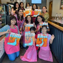 A group of participants, including kids and adults, proudly showing their autumn landscape paintings at a cafe workshop. My sessions are family friendly and open to all ages.