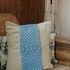 A beautiful sky-blue cushion tie-back with a repeating diamond knot pattern. This piece adds a lovely texture and a soft pop of color, making it a perfect accessory for a neutral-colored sofa or armchair.