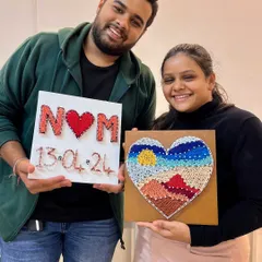 Our studio is the perfect spot for a creative date night. This happy couple proudly shows off the unique string art pieces they made together, a perfect memento of their special evening.