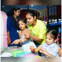 Our staff is always on hand to guide the children through activities. Here, a team member helps two girls with a creative slime or clay-making project.