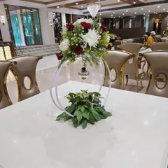 A close-up of a modern table centerpiece designed for a ring ceremony. This piece uses a white circular hoop frame, a mix of red and white flowers, and a hanging bauble for a contemporary look.