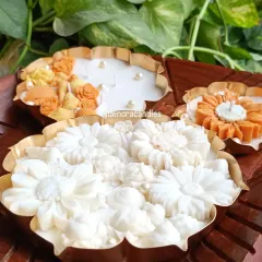 I offer urli candles in a variety of sizes and designs. Here you can see a large all-white floral urli, a smaller sunflower design, and a seashell-themed piece, showcasing the range of styles available.