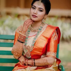 A beautiful portrait of an AMAIRA bride. Her custom orange blouse with subtle zardozi work perfectly matches the border of her cream-colored wedding saree.