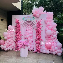 A beautiful "Pop of Pink" backdrop for a first birthday. The design features arches filled with pink balloons and columns of stunning pink cherry blossoms.