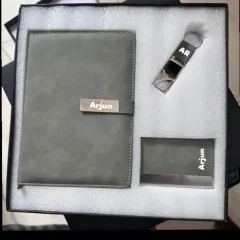 A complete corporate gift set including a personalized grey diary, a metal card holder, and a keychain, all engraved with the name 'Arjun'.