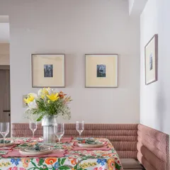 The dining nook in the 'Modern Muse' project, featuring a custom-built bench with pink channel-tufted upholstery. The space is set for a meal, showcasing its functionality and charm.