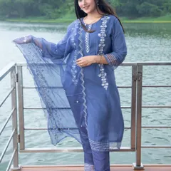 A full-length portrait of a model wearing a blue embroidered kurta set. This image from an outdoor fashion shoot captures the garment's details and fit in natural light.