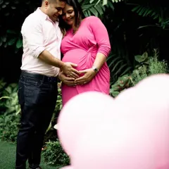 This couple used a vibrant pink dress and heart-shaped balloons for their gender reveal shoot, anticipating a baby girl. Using color and props is a fun way to build excitement and create memorable announcement photos.