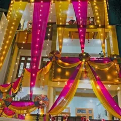 A complete wedding house transformation showcasing our expertise in large-scale fabric draping. We used bright pink and yellow drapes accented with fairy lights and traditional umbrellas to create a festive look that stands out, day and night.