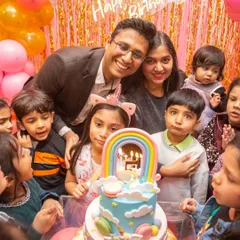 A precious moment as the family gathers around the birthday girl and her amazing rainbow cake.