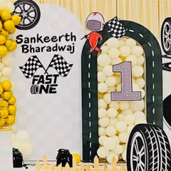 A personalized arch for Sankeerth Bharadwaj's "Fast One" birthday. The decor includes checkered flags, a racer cutout, and the child's name, making the theme feel extra special and customized.