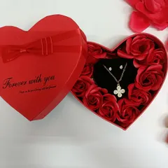 A closer look at the four-leaf clover necklace set, nestled among red roses. It's a symbol of good luck and love.