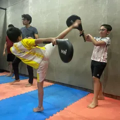 Students learn from each other in my classes. Here, one boy holds the kicking pad for his partner, helping him develop a powerful and accurate Taekwondo-style kick.