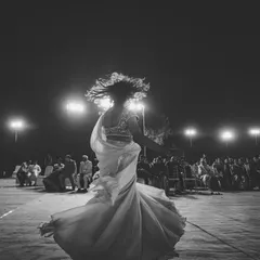 A black and white shot of a bride twirling on the dance floor during her sangeet. The motion blur and backlighting create a feeling of freedom and uninhibited happiness.