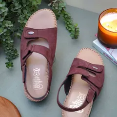 A lifestyle shot of the brown sandals in a calm, serene setting with a plant and a candle. This shows a different side of the product, focusing on comfort and well-being.