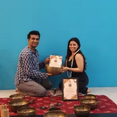 A student smiles as she receives her Sound Healing certification, ready to share the power of vibrational medicine.